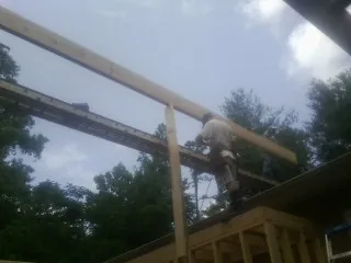 Carpenter setting a ridge beam over a new addition frame — Ice Dam Removal by Roofing Brothers in Peachtree Corners