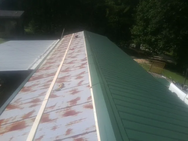 Old rusted panels beside newly installed green metal roofing — Wind Damage Roof Repair by Roofing Brothers in Peachtree Corners