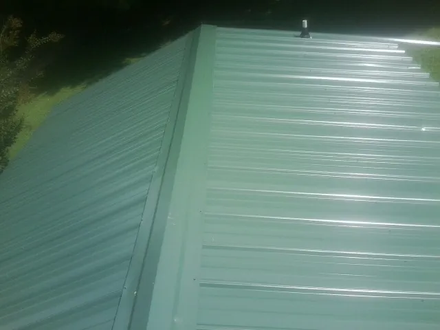New green metal panels meeting at the ridge of a roof — Flat Roof Repair work by our crew in Peachtree Corners