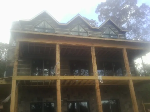 Dormers and porch framing on a large log home under construction — Roof Coating work by our crew in Peachtree Corners