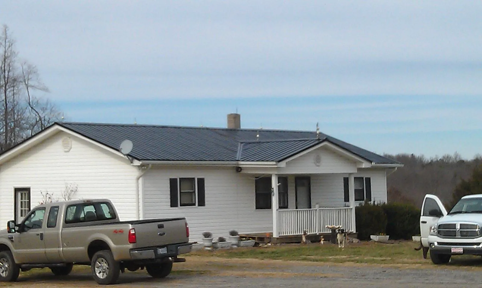 Finished dark metal roof on a white ranch home with work trucks parked in Peachtree Corners