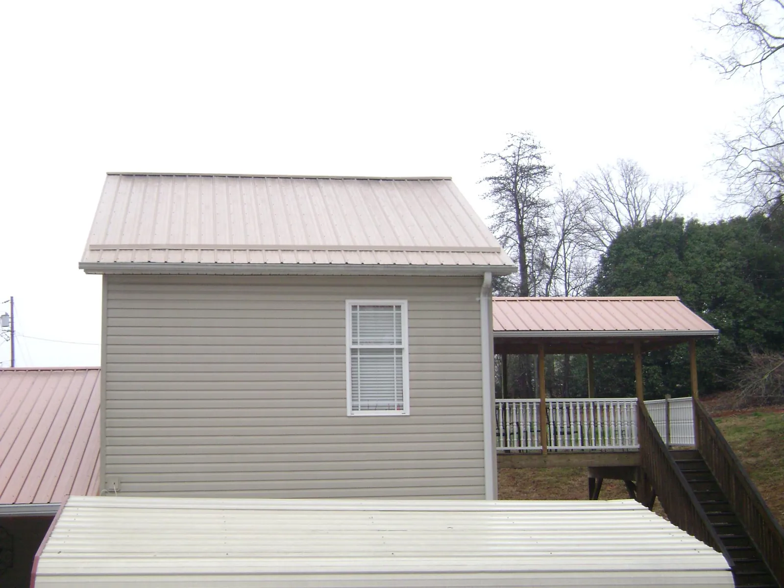 Tan metal roofs on a two story addition and attached porch, from a Roof Replacement job in Peachtree Corners