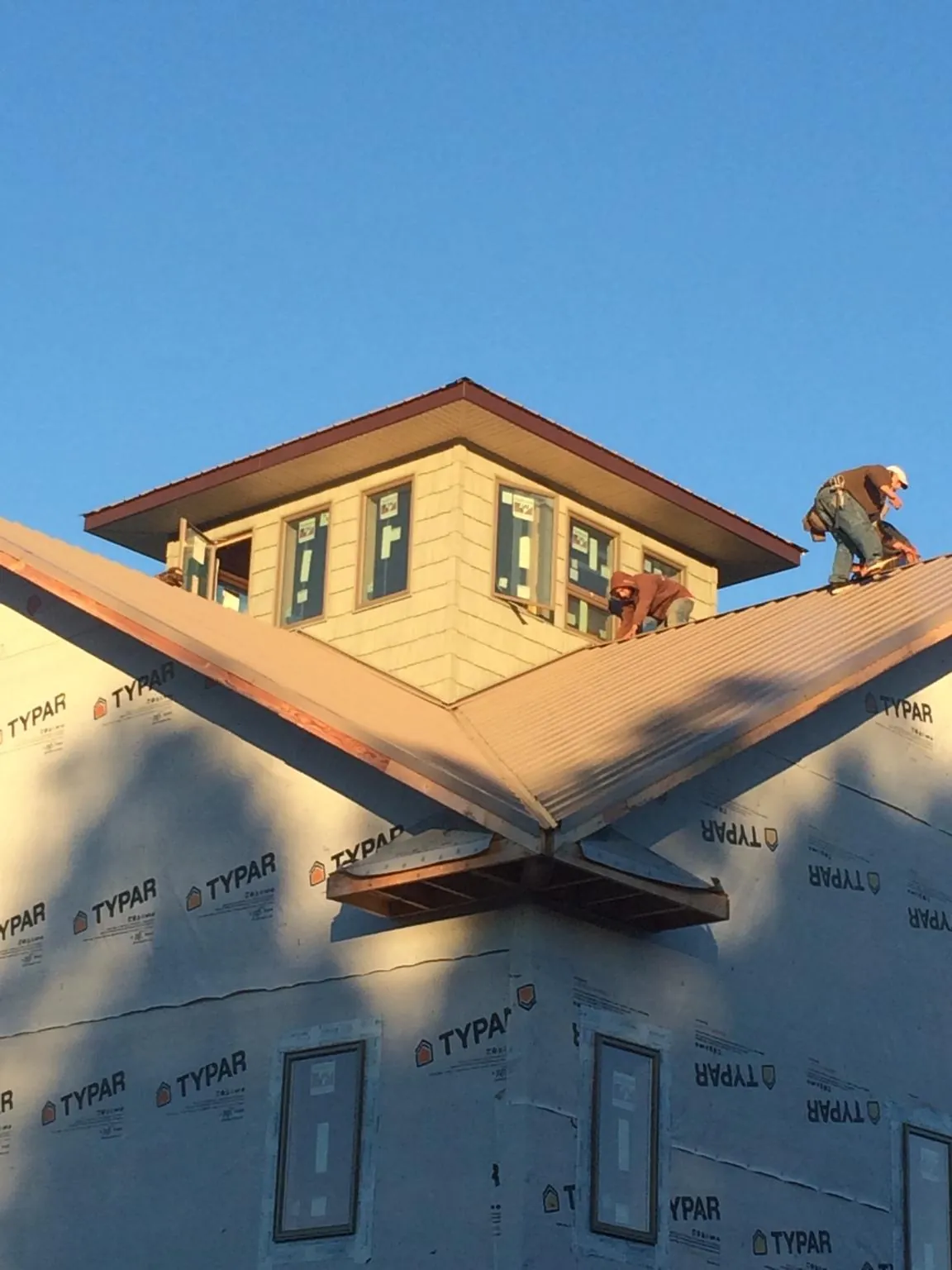 Roofers working around a rooftop cupola on a new metal roof at sunset — Roof Waterproofing in Peachtree Corners by Roofing Brothers